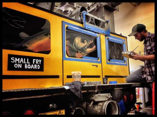 Hollis Swan helps to paint the back of the bus